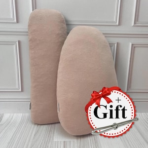 May include: Two large, light pink, fabric cushions. The cushion on the right has a red and white gift tag with the word "Gift" in black text.