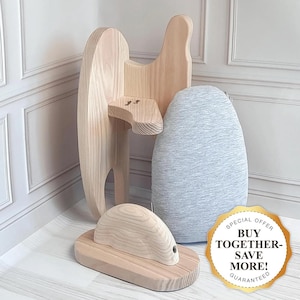 Può includere: Un giocattolo di cavallo a dondolo in legno con un cuscino grigio e bianco. Il cavallo a dondolo ha una base in legno e una testa in legno con una criniera scolpita. Il cuscino è posizionato sulla schiena del cavallo a dondolo. L'immagine include anche un adesivo dorato con il testo "ACQUISTA INSIEME - RISPARMIA DI PIÙ! GARANTITO".