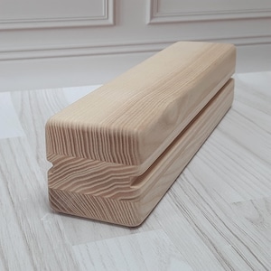 Può includere: Un blocco di legno naturale con una scanalatura tagliata nella parte superiore. Il blocco è in legno chiaro con una venatura naturale.