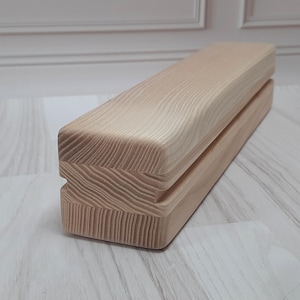 Può includere: Un blocco di legno con una scanalatura al centro, realizzato in legno chiaro con una venatura naturale.