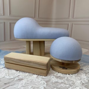 May include: A light blue fabric-covered tailor's ham and sleeve roll set with natural wood bases. The set includes a curved pressing cushion, a dome-shaped pressing tool, and a rectangular wooden block, all featuring smooth, light-colored wood.