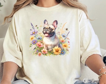May include: A white t-shirt featuring a graphic of a French bulldog sitting in a field of flowers. The flowers are pink, purple, yellow and blue.
