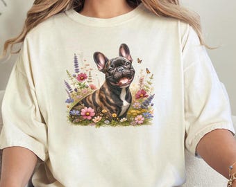 May include: A white t-shirt featuring a graphic of a French bulldog surrounded by flowers and butterflies.