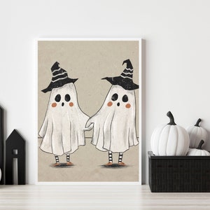 May include: Two white ghosts wearing black and white witch hats with orange and black striped legs. The ghosts are holding hands and smiling. The image is on a beige background.