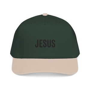 Peut inclure: Une casquette de baseball vert foncé avec une visière beige clair et un petit bouton assorti sur le dessus. Le mot JESUS est imprimé en caractères gras, noirs et sans empattement au centre de l'avant. La casquette a une calotte structurée.