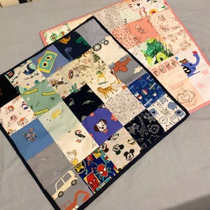 May include: Two baby quilts made from fabric scraps. The larger quilt is pink with a variety of patterns and the smaller quilt is blue with a variety of patterns. The smaller quilt has a dark blue border.