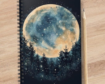 Puede incluir: Una libreta espiral negra con una ilustración de acuarela de una luna llena con estrellas y una silueta de un bosque delante de ella.