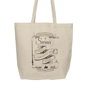 May include: A beige canvas tote bag with a black and gold graphic print of a wand, a castle, and the text "I solemnly swear that I am up to no good The Marauder's Map".