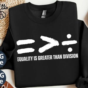 May include: Black sweatshirt with the slogan "Equality is Greater Than Division" in white. The design includes mathematical symbols: equals, greater than, and division. The sweatshirt is displayed on a neutral surface.