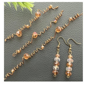 Puede incluir: Tres diademas de alambre dorado con cuentas de vidrio marrón y un par de pendientes colgantes dorados con cuentas de vidrio marrón y transparentes.