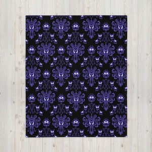 May include: A black and purple patterned throw blanket with a repeating design of a ghost face and a spooky mansion.