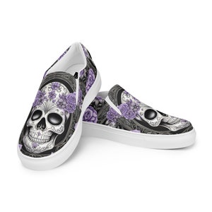 Könnte beinhalten: Weiße Canvas-Slipper mit einem schwarzen und weißen Totenkopfdesign mit lila Blumen. Der Totenkopf hat ein Zucker-Schädel-Design mit komplizierten Details.