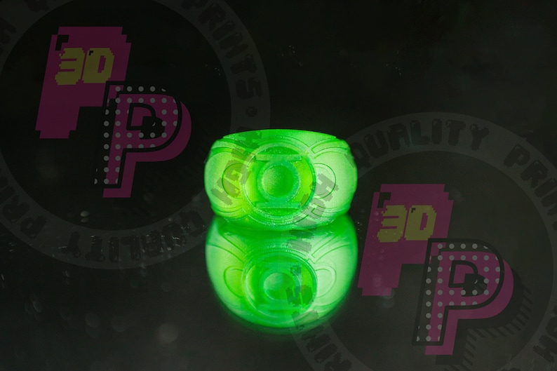Pu&ograve; includere: Un anello verde neon brillante con l'emblema circolare di Lanterna Verde sulla parte anteriore. L'anello ha un aspetto liscio e traslucido ed &egrave; mostrato con un riflesso chiaro sulla superficie sottostante, che mette in risalto il suo colore.