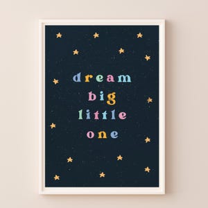 May include: A dark blue poster with gold stars and the text "dream big little one" in colorful letters.