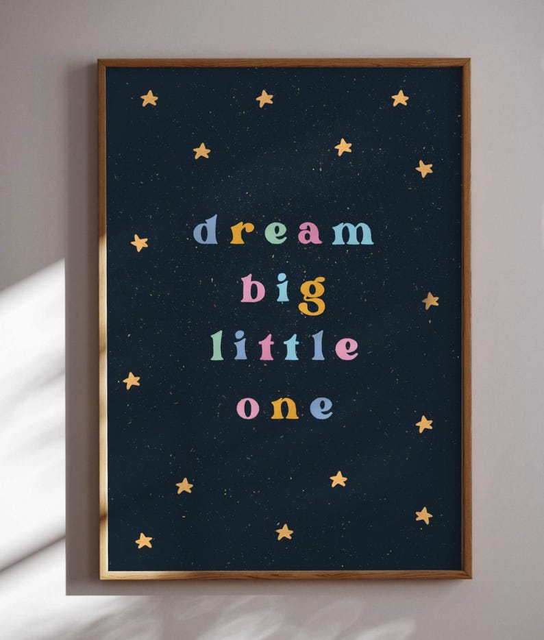 May include: A framed print with a dark blue background and gold stars. The text "dream big little one" is written in colorful letters.