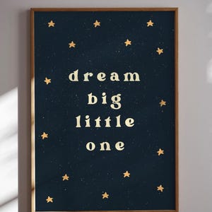 May include: A dark blue poster with gold stars and the text "dream big little one" in white.