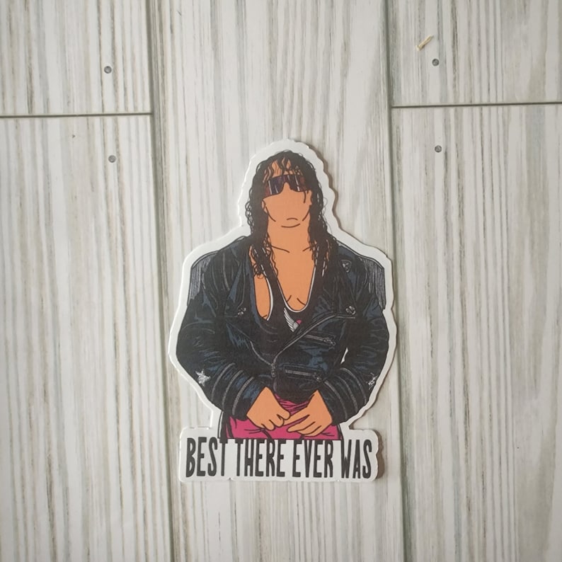 May include: A black and white sticker of a wrestler wearing a black leather jacket and sunglasses. The text "BEST THERE EVER WAS" is below the image.