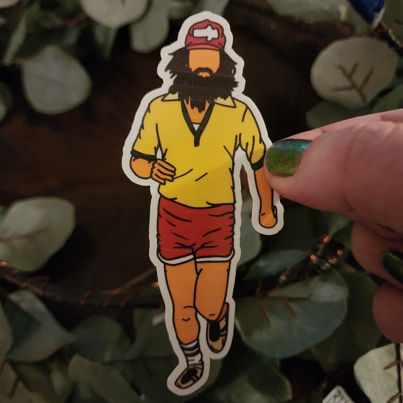 K&ouml;nnte beinhalten: Ein Aufkleber mit einer Comicfigur, die ein gelbes Hemd, rote Shorts und eine rote M&uuml;tze mit einem wei&szlig;en Pfeil nach links tr&auml;gt. Die Figur hat einen langen braunen Bart und rennt.