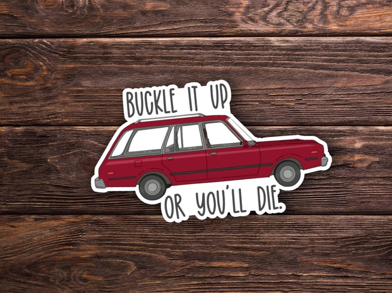 May include: A red station wagon with a white roof rack and the text "Buckle it up or you'll die." printed on the sticker.