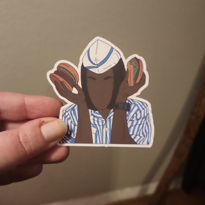 May include: A sticker of a person wearing a blue and white striped shirt and a white hat with a blue stripe. The person is holding two hamburgers, one in each hand.