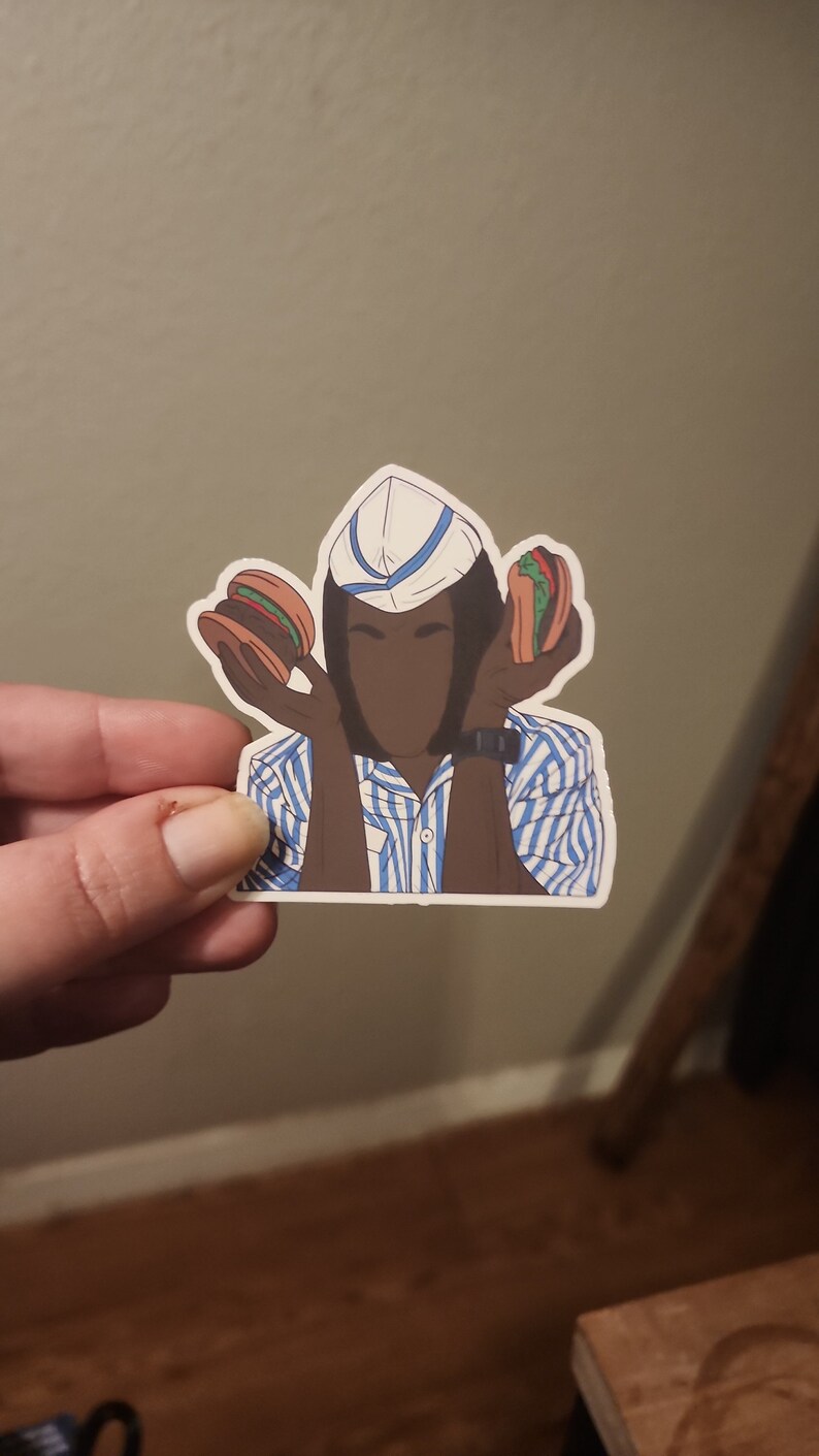 May include: A sticker of a person wearing a blue and white striped shirt and a white hat with a blue stripe. The person is holding two hamburgers, one in each hand.