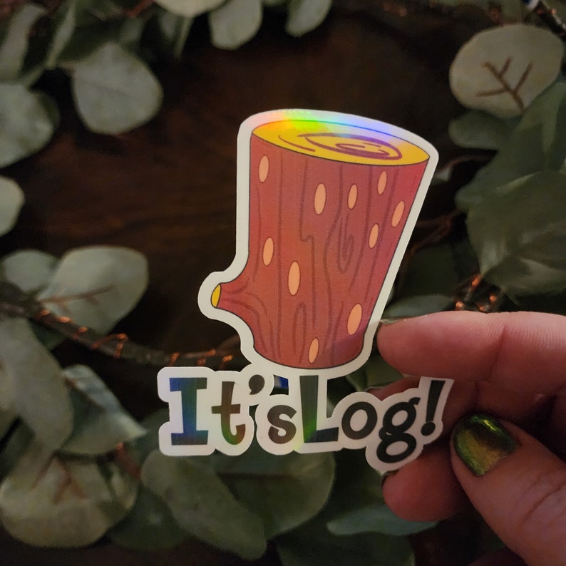 Pu&ograve; includere: Adesivo olografico con un design a forma di tronco di cartone animato e la scritta "It's Log!". Il tronco &egrave; marrone con un centro giallo e piccoli dettagli ovali. L'adesivo ha una finitura lucida e iridescente.