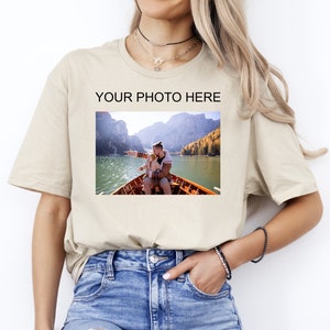 May include: A beige t-shirt with a photo of a man and a child in a boat on a lake. The text "YOUR PHOTO HERE" is printed above the photo.