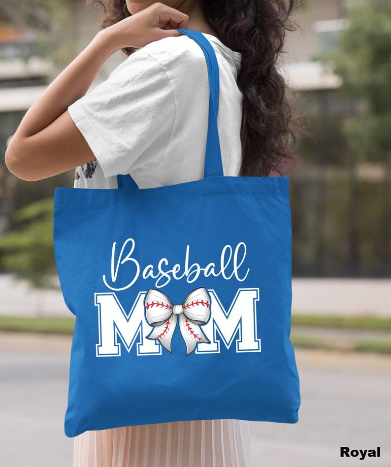 May include: A royal blue tote bag with white text that reads "Baseball Mom" and a white baseball-themed bow with red stitching.