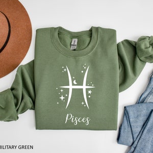 Op de afbeelding: Een groen sweatshirt met een wit Vissen-sterrenbeeld en het woord "Vissen" gedrukt op de voorkant.