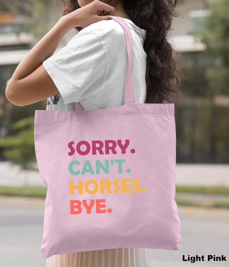K&ouml;nnte beinhalten: Eine hellrosa Tragetasche mit dem Text "SORRY. CAN'T. HORSES. BYE." in bunten Buchstaben.