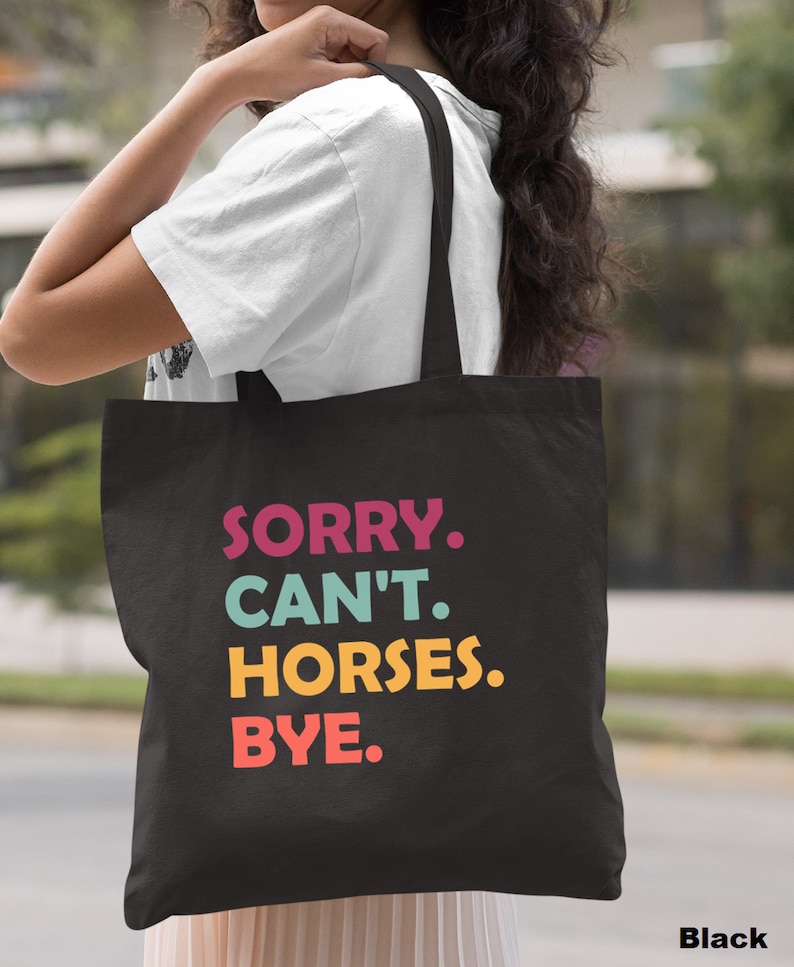 K&ouml;nnte beinhalten: Schwarze Einkaufstasche mit dem Text "SORRY. CAN'T. HORSES. BYE." in bunten Buchstaben.