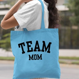 May include: Light blue tote bag with black text that reads "TEAM MOM".