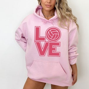May include: Pink hoodie with a pink graphic of the word "LOVE" with a volleyball in the "O".