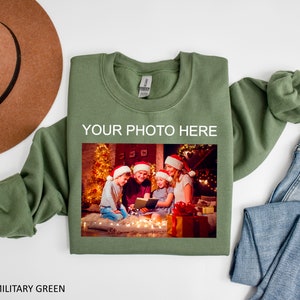May include: A green sweatshirt with the text "YOUR PHOTO HERE" and a photo of a family in front of a Christmas tree.
