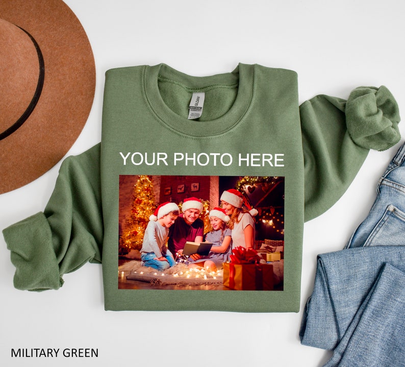 May include: A green sweatshirt with the text "YOUR PHOTO HERE" and a photo of a family in front of a Christmas tree.
