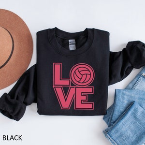 May include: Black sweatshirt with a pink graphic of the word "LOVE" with a volleyball in the "O".