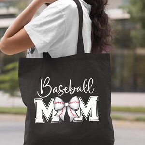 May include: Black canvas tote bag with white text that reads "Baseball Mom" and a white baseball-themed bow.