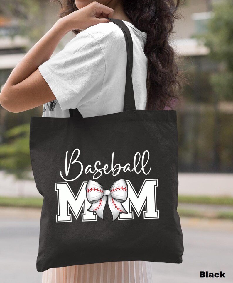 May include: Black canvas tote bag with white text that reads "Baseball Mom" and a white baseball-themed bow.