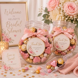May include: Two clear glass jars filled with gold-wrapped chocolates and pink heart-shaped candies, each tied with a light pink satin ribbon and a circular label reading Thank You For Celebrating With Us, accompanied by a clear plastic scoop.