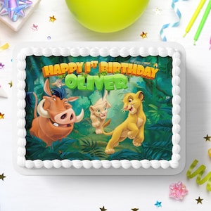 Könnte beinhalten: Ein weißer Kuchen mit einem essbaren Bild von Simba, Pumbaa und Timon aus dem König der Löwen. Der Kuchen ist mit weißem Frosting verziert und dem Text "Happy 1st Birthday Oliver".