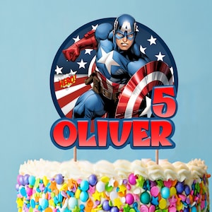 Op de afbeelding: Een rode, witte en blauwe taarttopper met Captain America met de tekst "HERO!" en "OLIVER 5".