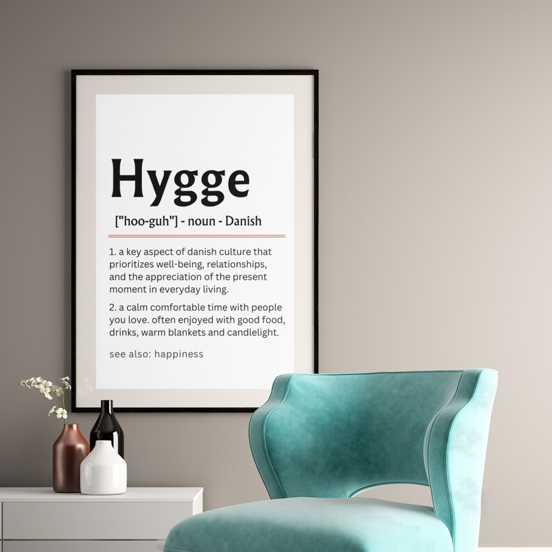 May include: A black and white printable poster with the word "Hygge" in a large, bold font. The definition of the word is provided in a smaller font below, along with the pronunciation and the origin of the word. The definition describes hygge as a key aspect of Danish culture that prioritizes well-being, relationships, and the appreciation of the present moment in everyday living. It also describes hygge as a calm, comfortable time with people you love, often enjoyed with good food, drinks, warm blankets, and candlelight. The poster also includes the phrase "see also: happiness".