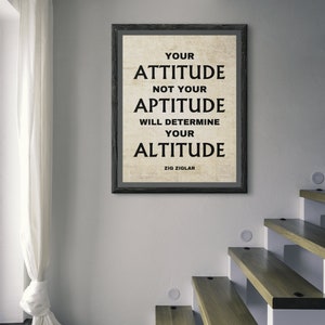 Puede incluir: Un póster de cita motivacional enmarcado en negro con fondo blanco. La cita dice "Tu actitud, no tu aptitud, determinará tu altitud." La cita se atribuye a Zig Ziglar.