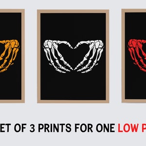 Puede incluir: Conjunto de tres impresiones de arte imprimibles que presentan una mano de esqueleto haciendo una forma de corazón. Las impresiones están sobre un fondo negro con las manos de esqueleto en naranja, blanco y rojo.