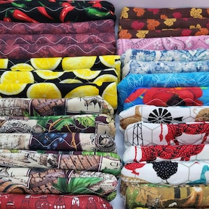 May include: A stack of colorful quilted fabric pot holders with various patterns, including lemons, grapes, and farm animals. The pot holders are made of cotton fabric and are quilted for durability.