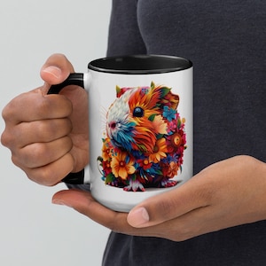May include: A white ceramic mug with a black rim and handle. The mug features a colorful illustration of a guinea pig with flowers.