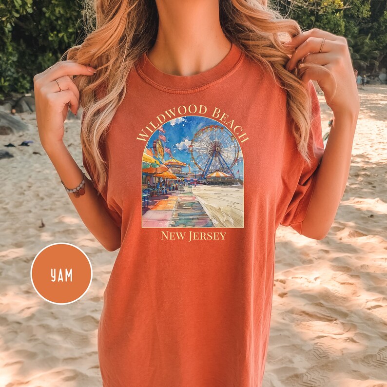 May include: A rust-colored t-shirt with a graphic of a Ferris wheel and boardwalk scene. The text "Wildwood Beach New Jersey" is printed on the shirt.