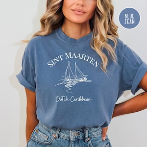 May include: A blue jean t-shirt with white text that reads "Sint Maarten Dutch Caribbean" and a white illustration of a sailboat.