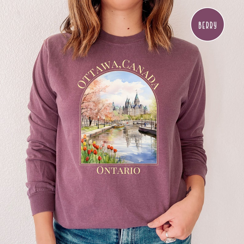 May include: A purple long-sleeved sweatshirt with a graphic print of the Parliament Building in Ottawa, Canada. The graphic includes the text "OTTAWA, CANADA" and "ONTARIO".