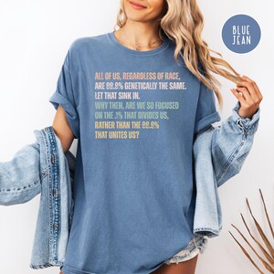 May include: A blue t-shirt with the text "ALL OF US, REGARDLESS OF RACE, ARE 99.9% GENETICALLY THE SAME. LET THAT SINK IN. WHY THEN, ARE WE SO FOCUSED ON THE .1% THAT DIVIDES US, RATHER THAN THE 99.9% THAT UNITES US?"